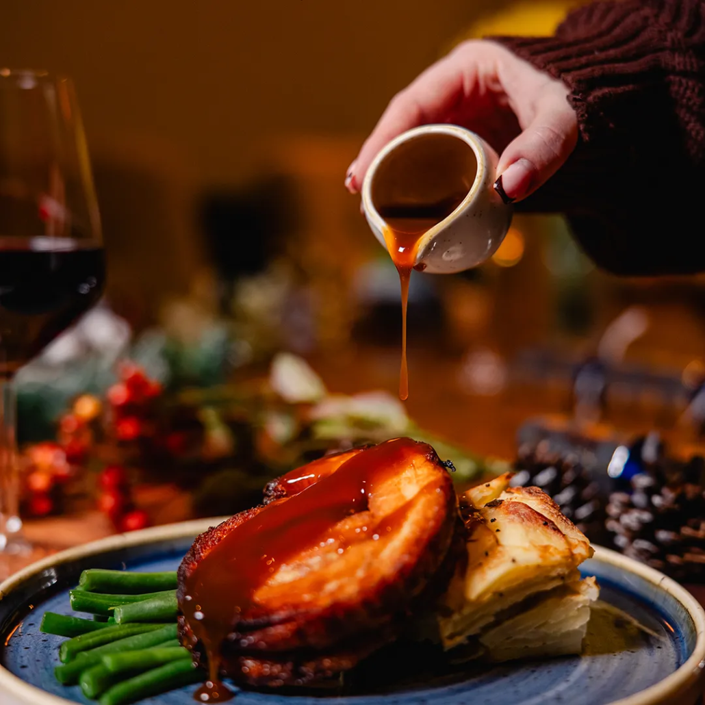 The Dock's Cranberry Glazed Pork Belly Festive Menu Main Slow cooked pork belly glazed with cranberry, served with Brussels sprout mash, crispy crackling, Tenderstem broccoli & Gwynt Y Ddraig Orchard Gold Cider jus.